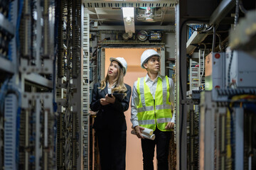 Wall Mural - By designing intricate electrical circuits, Asian male and female engineers are revolutionizing power plants and helping the energy industry meet the world’s energy challenges.