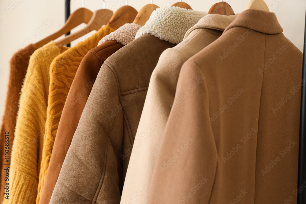 Rack with winter clothes near light wall, closeup