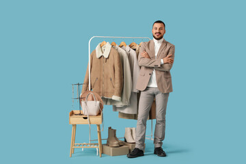 Wall Mural - Male stylist with warm clothes and accessories on blue background