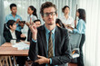 © Summit Art Creations - Portrait of happy businessman looking at camera, making finger pointing gesture for advertising product with motion blur background of business people movement in dynamic business meeting. Habiliment