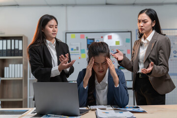 Wall Mural - Stressed asian businesswomen argue in office, one with headache, showing pressure of corporate world. Feelings of frustration, anger, sadness evident. Woman looks tired, exhausted, worried