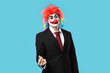 © Pixel-Shot - Young man as clown businessman making heart with fingers on blue background