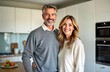 © miss irine - Middle-aged couple smiles happily in modern kitchen. Couple relaxed together in home. Casual attire suggests comfort, warmth. Healthy lifestyle evident in positive expression. Content family