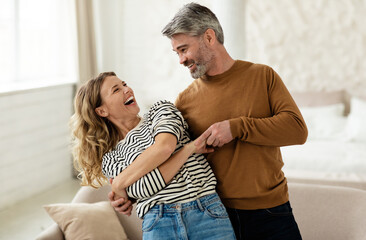 joyful couple dancing having fun at home. loving husband and wife having date hugging and laughing i