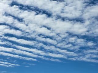 fluffy white clouds lie in stripes against the blue sky