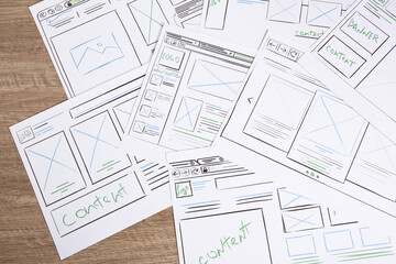 Leinwandbilder - Developing UI design. Sketches of website wireframes on wooden table, top view