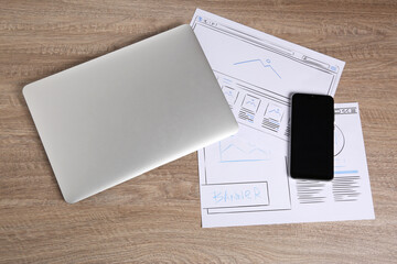 Leinwandbilder - Developing UI design. Sketches of website wireframes, laptop and smartphone on wooden table, top view