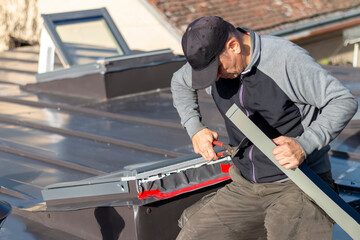 A craftsman covers the roof window with sheet metal. Roofer and window master work.