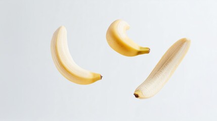 Poster - three ripe bananas floating in mid-air against a light background showcasing their vibrant yellow co