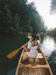 Wall Mural - Couple paddling canoe in the river forest