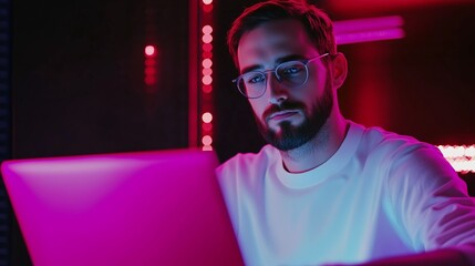 Poster - young man working intently on laptop in a vibrant, neon-lit environment during nighttime