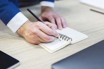 Aufkleber - Detailed view of a man's hand jotting notes in a notepad, with a blurred background
