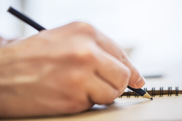 Aufkleber - Close perspective of a man's hand making entries in a notepad, with a soft blur in the surrounding