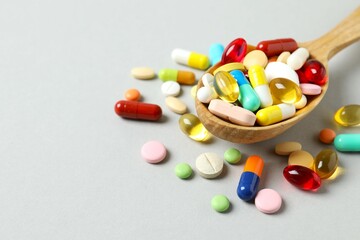 Wall Mural - Various medicine pills and capsules in spoon on gray background 