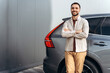 © Maria Vitkovska - Smiling, bearded man standing near car with crossed arms looking at camera. Insurance concept