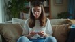 © Влада Яковенко - An upset young woman is sitting on the sofa at home and looking disappointedly at the fake pregnancy test she is holding in her hands