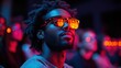 © Aziz - Man with glasses in a dark room, illuminated by red and blue light.