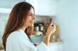 © Dragana Gordic - Woman Enjoying Healthy Breakfast in a Cozy Home Kitchen Setting