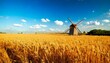 © FCEalin  - Peaceful rural countryside with fields of golden wheat and a windmill under a blue sky.