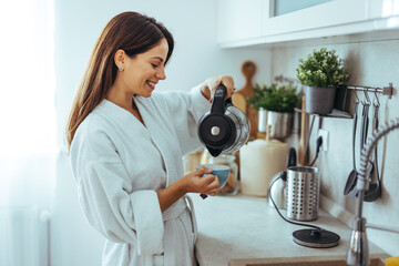 Wall Mural - Woman Smiling While Pouring Coffee in Modern Kitchen Setting