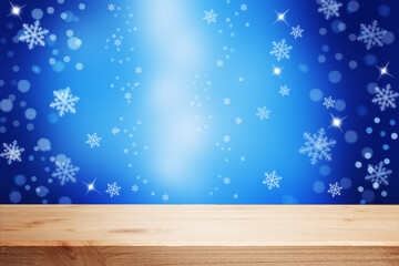 festive christmas blue background with an empty wooden table, lights, and snowflakes.