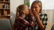 © Yuliia - Mischievous Caucasian girl child whispering secret in ear female mother mom shocked surprised woman listen little daughter gossip telling interesting story rumor kid speak with parent at home family