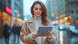 © Akash Tholiya - Young smart busy businesswoman executive, female company worker or manager holding digital tablet using pad technology device working standing in modern corporate office