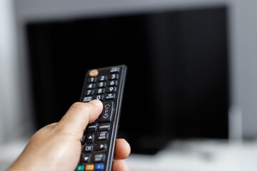 close up Television remote control in casual young female yellow shirt hands pointing to tv set and turning it on or off. select channel watching tv on sofa at home in the living room relax.