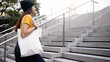© ChayTee - Go green Gen Z woman asia young people carrying eco tote bag reuse step walk up stairs in city life save the earth planet world care. Reduce garbage issues asian hope net zero waste the way forward.