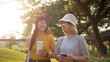 © ChayTee - Go green two asia people happy woman talk walk fun in city life sun light tree public park. Future asian hope the way forward save the earth net zero waste reduce issues by reuse bottle eco tote bag.