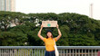© ChayTee - Go green Gen Z woman asia young people looking at camera stress showing save the earth planet world care banner poster sign in city nature tree. Protect global warming future asian hope net zero waste