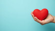 © fotoluigi868 - A female hand cradles a red heart on a soft pastel blue background, leaving room for text or advertisement in the vacant space._00001_