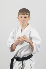 Fifteen year old male teenage karate black belt ready to spar, studio shot against a white background