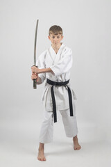 Fifteen year old male teenage karate black belt using a katana, studio shot against a white background