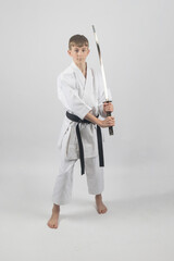 Fifteen year old male teenage karate black belt using a katana, studio shot against a white background