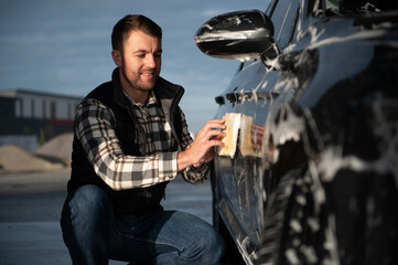 Wall Mural - A man washes a car with a sponge at a self-service car wash