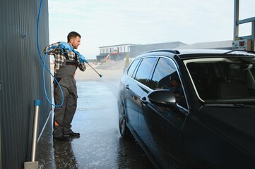 Man worker washing car service. Car wash cleaning station high pressure water. Employees clean a vehicle professionally