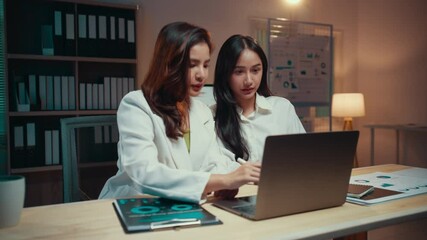 Aufkleber - Two businesswomen work late in the office, analyzing data on a laptop and discussing their project. Collaboration and focus drive their efforts as they navigate deadlines and strategy