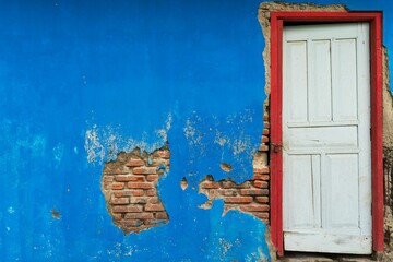 Weathered door in blue wall with exposed bricks.