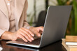 © Pixel-Shot - Female author using laptop at table in cafe, closeup