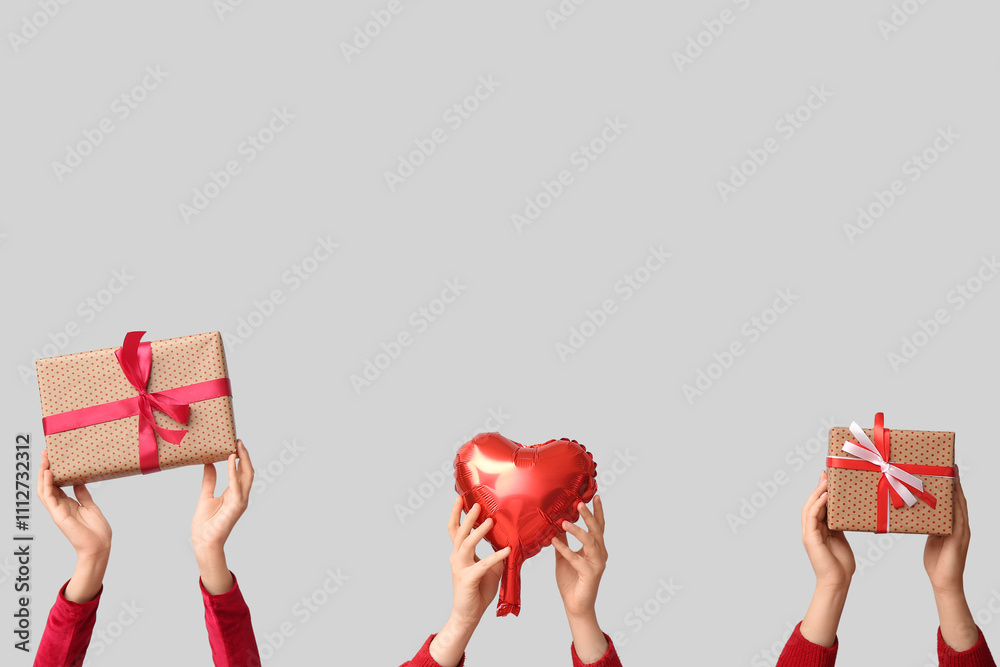 Female hands with gift boxes and heart-shaped air balloon on white background. Valentine's Day celebration