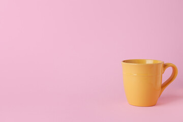 Wall Mural - Yellow ceramic empty mug on pink background