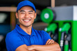 © Tanya - Middle-aged Asian gas station employee in a blue uniform, offering customer service with a smile at a busy service station.