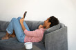 © Elena Kharichkina/Stocksy - Relaxed woman enjoying her phone on a cozy sofa