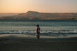 © Luis Herrera/Stocksy - woman standing at dawn in front of the ocean