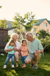 © Iuliia Versta/Stocksy - grandparents with their granddaughters playing on a backyard