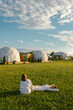 © Alina Hvostikova/Stocksy - Two women relax on the grass in front of glamping hotel