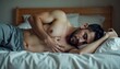 © Elena - Man lying in bed, curled up with hand over his heart, soft neutral tones evoking discomfort