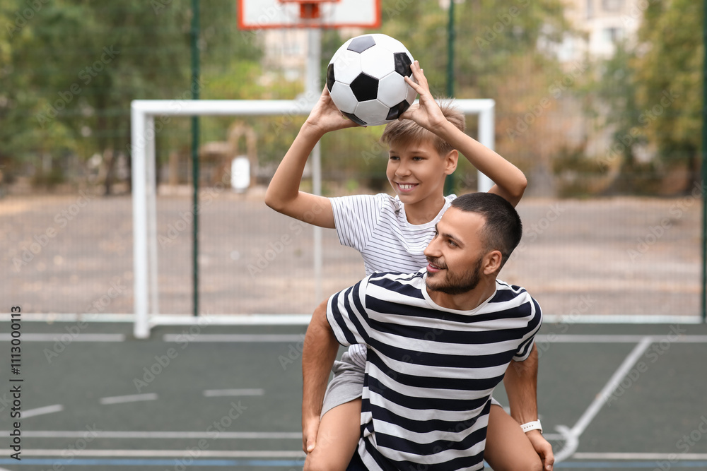 Happy father and son with soccer ball on pitch