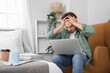 © Pixel-Shot - Stressed young man working with laptop in bedroom